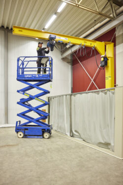 Man som befinner sig på en saxlift och reparerar en telfer