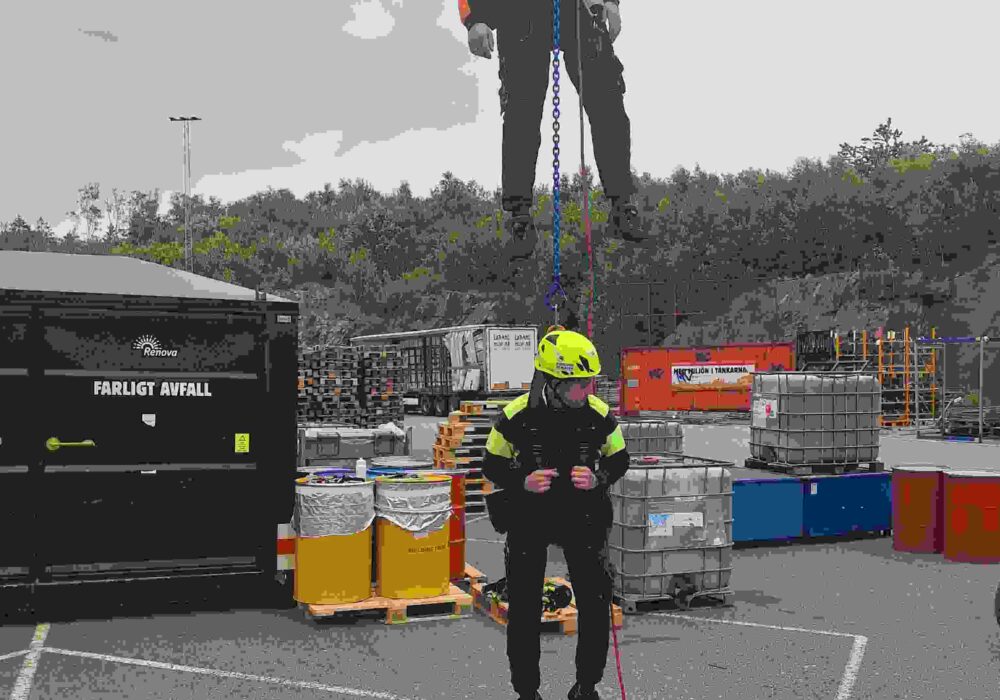 Bilden visar två personer som går en fallskyddsutbildning och hänger i fallskyddsutrustning