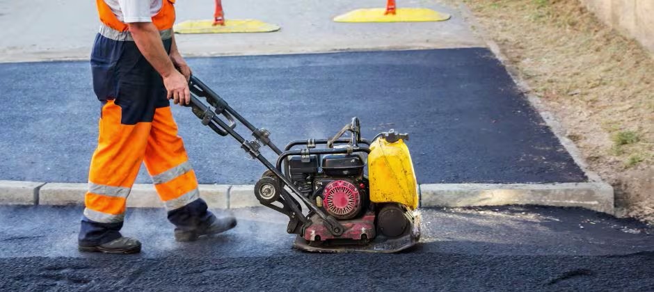 Medarbetare som arbetar vid väg med asfalt